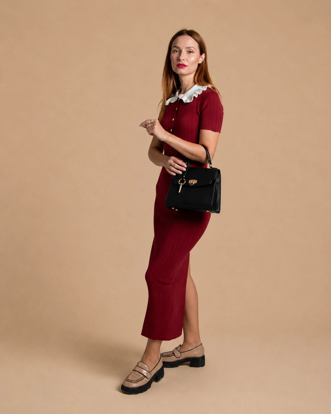 Woman wearing The Beatrice black genuine leather handbag, styled with a burgundy dress and classic loafers. Elegant leather bag for women featuring a structured silhouette, top handle and timeless everyday versatility.