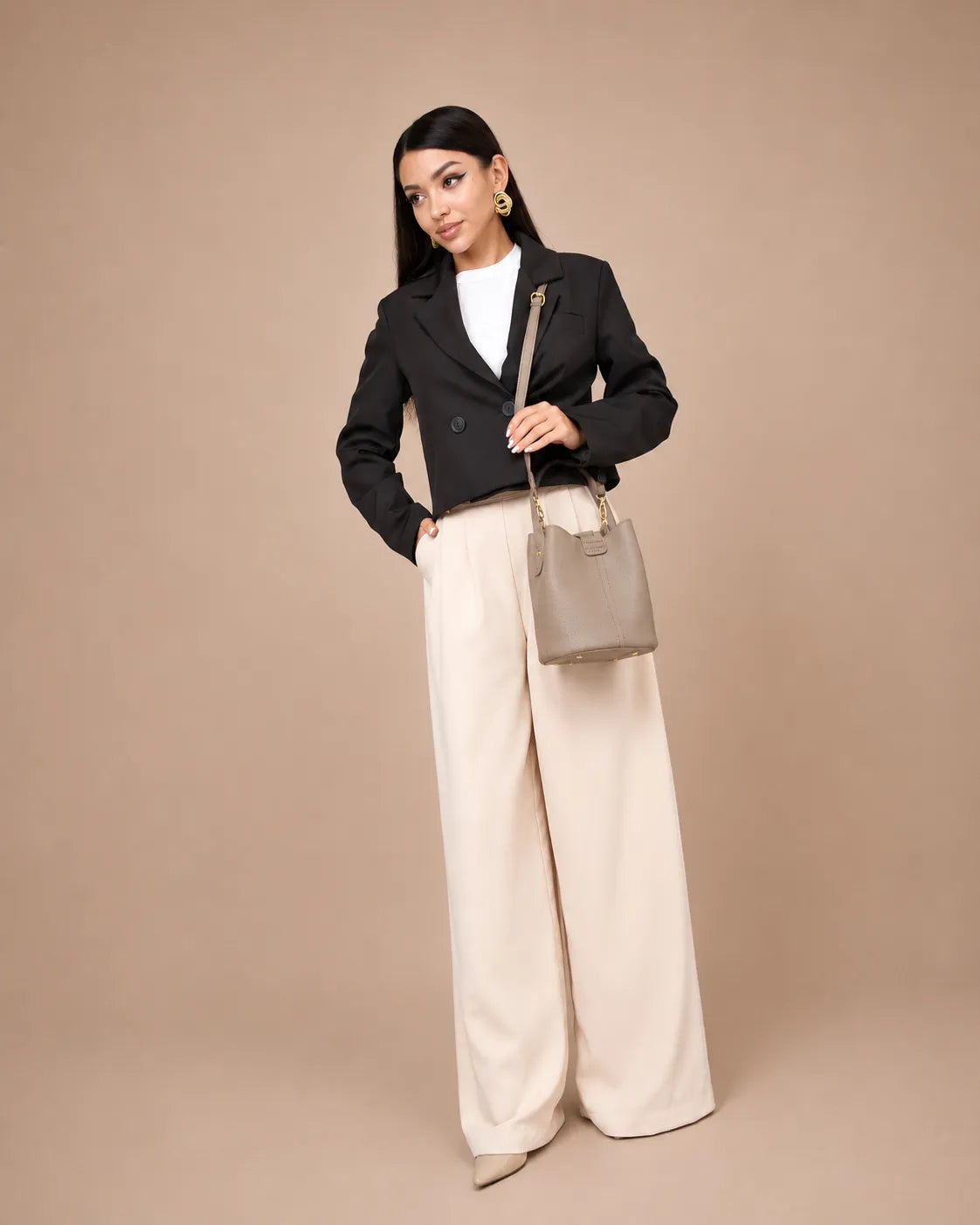Woman wearing The Charlotte elephant gray genuine leather bucket bag with a tailored black blazer and wide-leg trousers. Elegant leather handbag for women designed for everyday wear, modern city style and timeless sophistication.