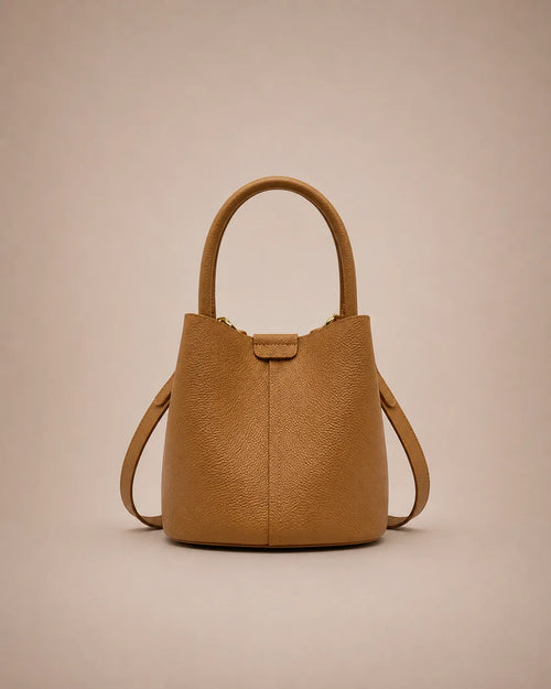 Charlotte genuine leather bucket bag in cookie brown featuring a timeless silhouette, top handle and adjustable shoulder strap.