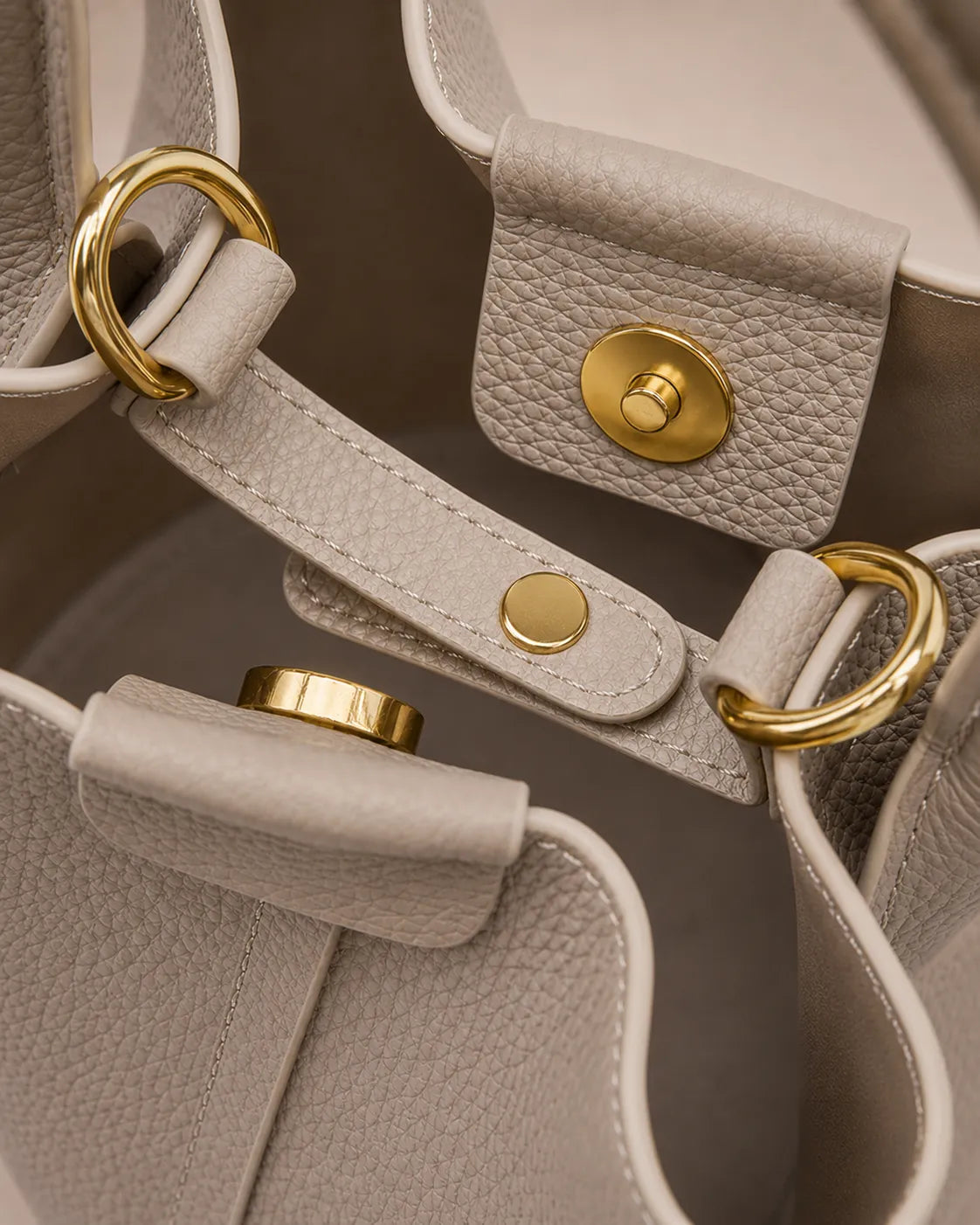 Close-up of the Charlotte leather bucket bag in elephant gray featuring a secure magnetic closure, premium gold-tone hardware and textured leather craftsmanship.