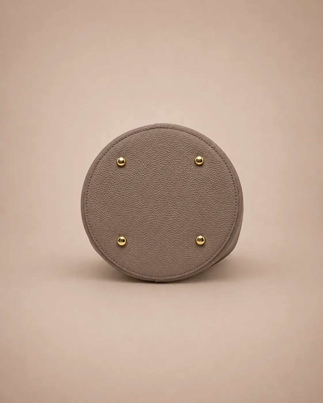 Bottom view of the Charlotte leather bucket bag in elephant gray showcasing protective metal feet and premium leather craftsmanship.