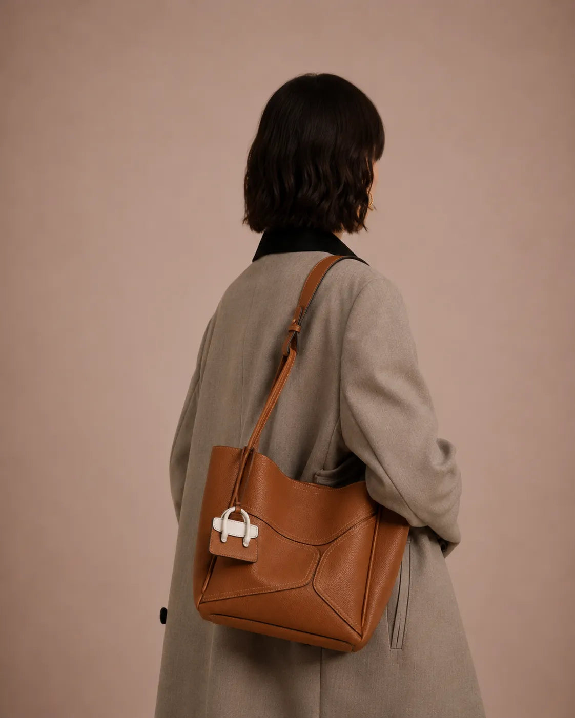 Woman wearing The Delphine cookie genuine leather handbag over the shoulder. Elegant women's leather handbag designed for everyday sophistication, workwear styling and timeless luxury.