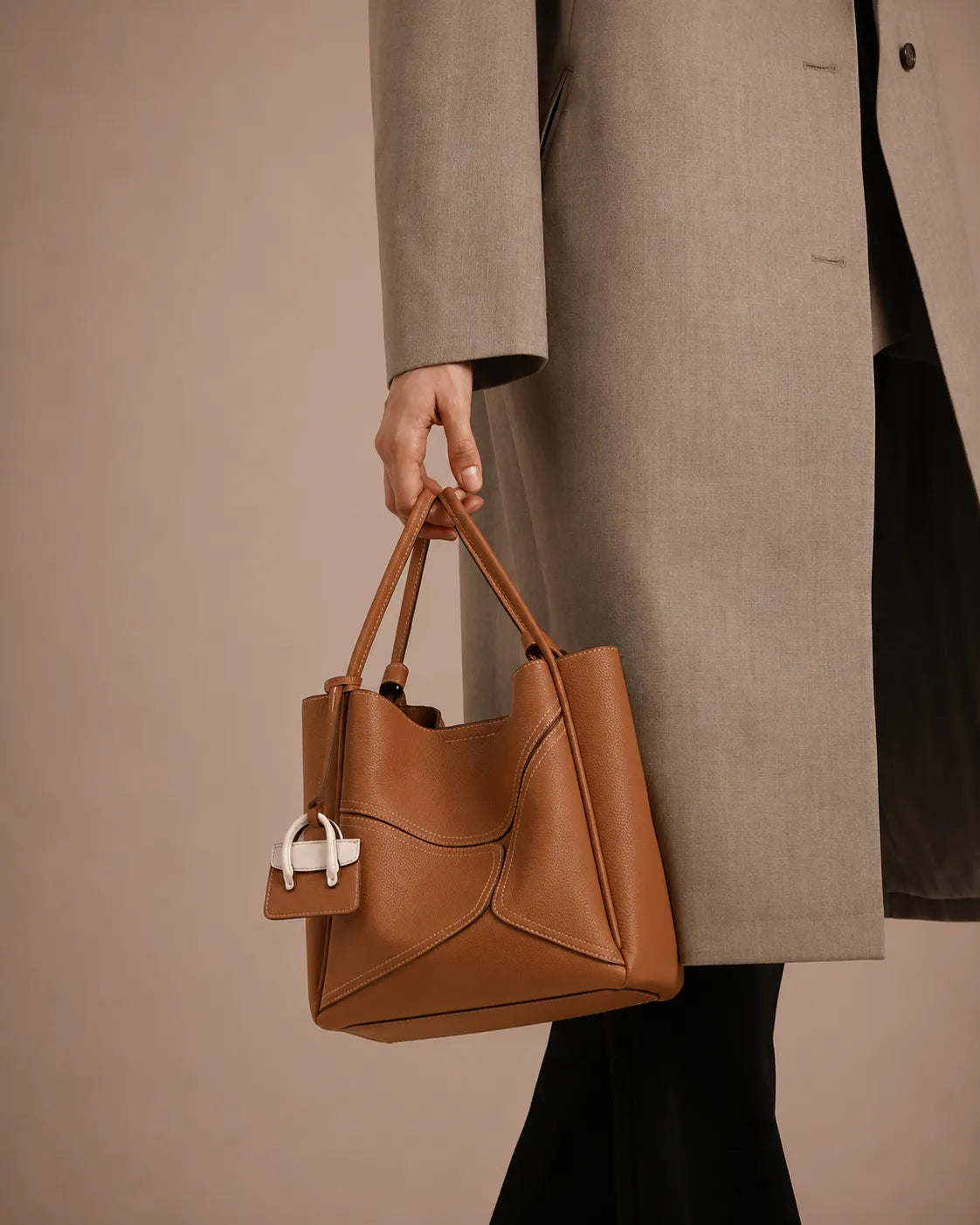 Woman carrying The Delphine cookie leather handbag by hand. Refined leather handbag for women featuring premium craftsmanship, spacious functionality and effortless everyday elegance.