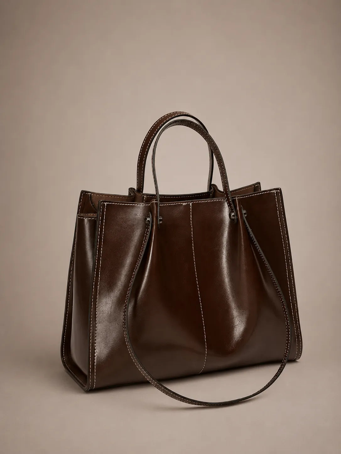Angled front view of the Edith Leather Tote Bag in Dark Chocolate genuine leather, featuring a refined silhouette, contrast stitching and timeless city-inspired design from The City Edit collection by Malena London.