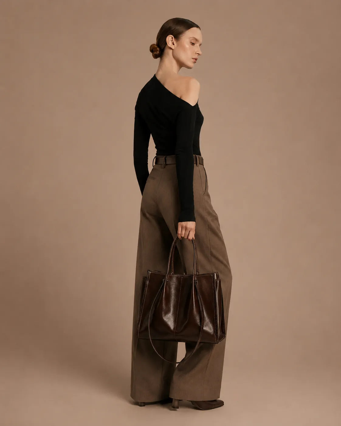 Woman carrying the Edith Leather Tote Bag in Dark Chocolate genuine leather, showcasing its elegant proportions and versatile city-ready design from The City Edit collection by Malena London.