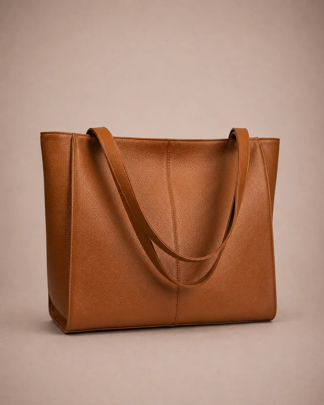 Three-quarter view of the Eleanor genuine leather tote bag in Brown featuring long shoulder straps, spacious interior capacity and refined minimalist styling. Premium women's leather tote bag ideal for work, commuting and travel.