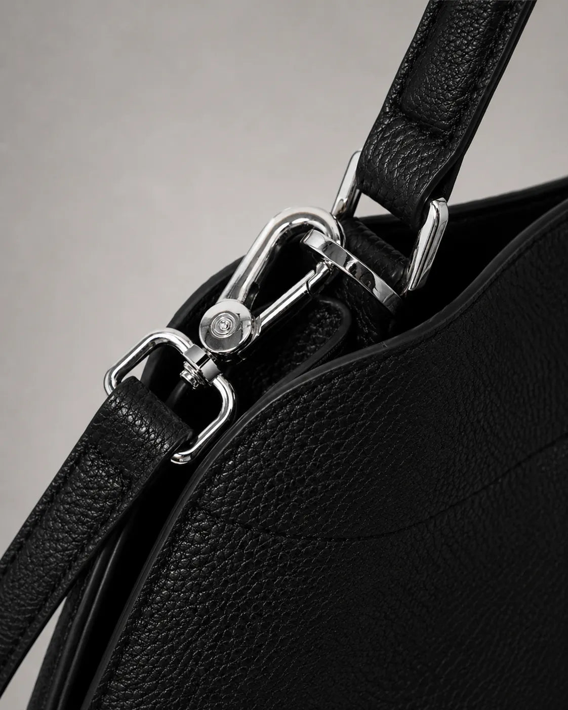 Close-up hardware detail of the Eliza genuine leather shoulder bag in Black, showcasing premium silver-tone hardware, removable strap attachment, textured pebbled leather and refined craftsmanship by Malena London.