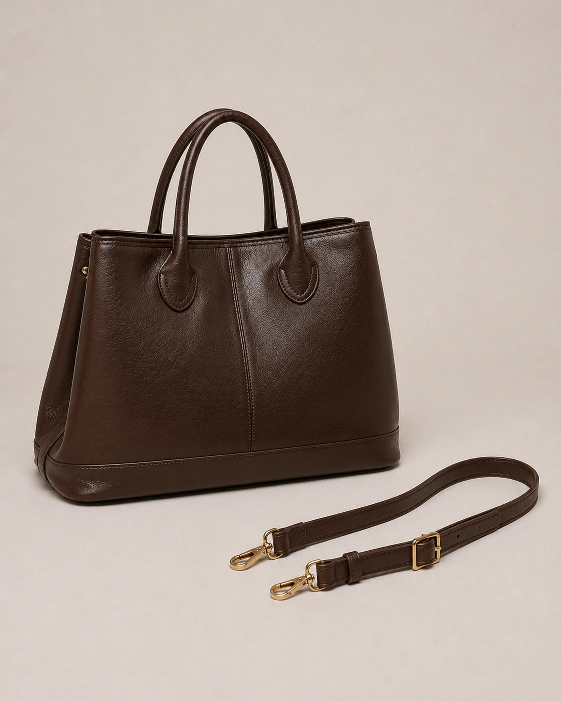 Angled view of the Odile large structured genuine leather tote bag in chocolate with the crossbody strap laid out.