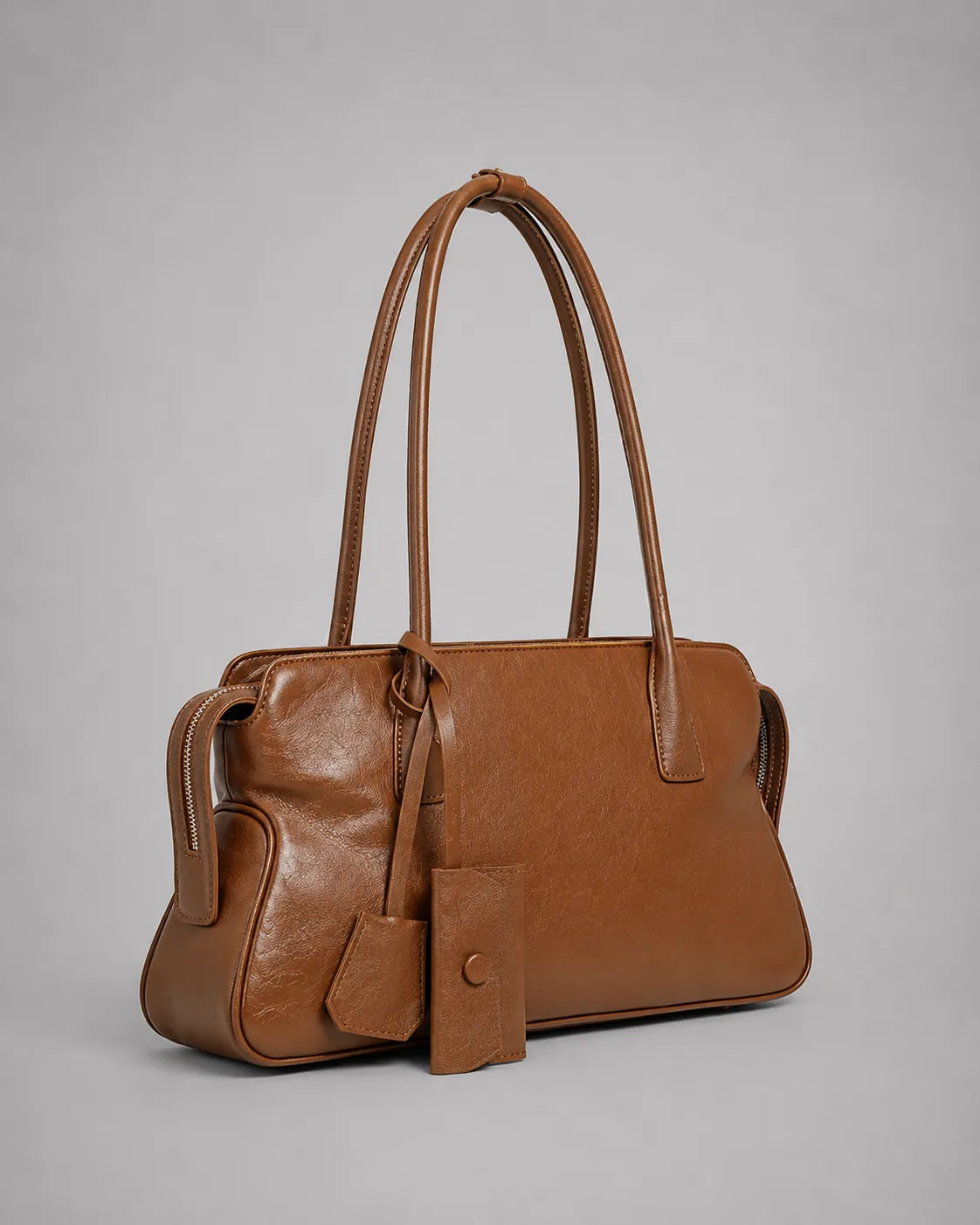 Georgia leather shoulder bag in Brown genuine leather shown in a front side angle highlighting the softly structured shape, elegant shoulder carry design, leather charms and refined everyday styling from the Soft Structure collection by Malena London.