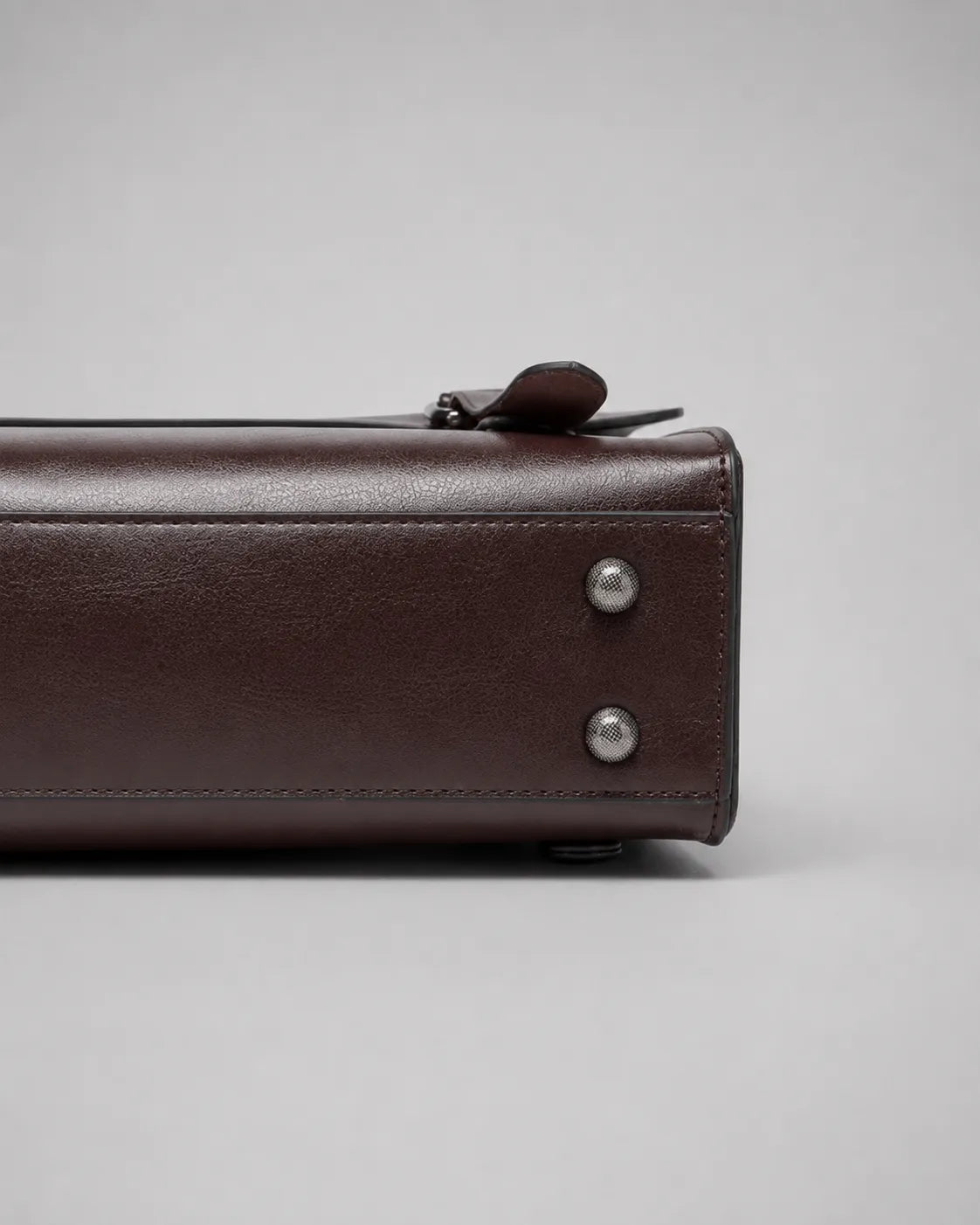 Base detail of the Heritage Leather Backpack in Dark Chocolate genuine leather, highlighting the structured construction, reinforced stitching, protective metal feet and premium craftsmanship.