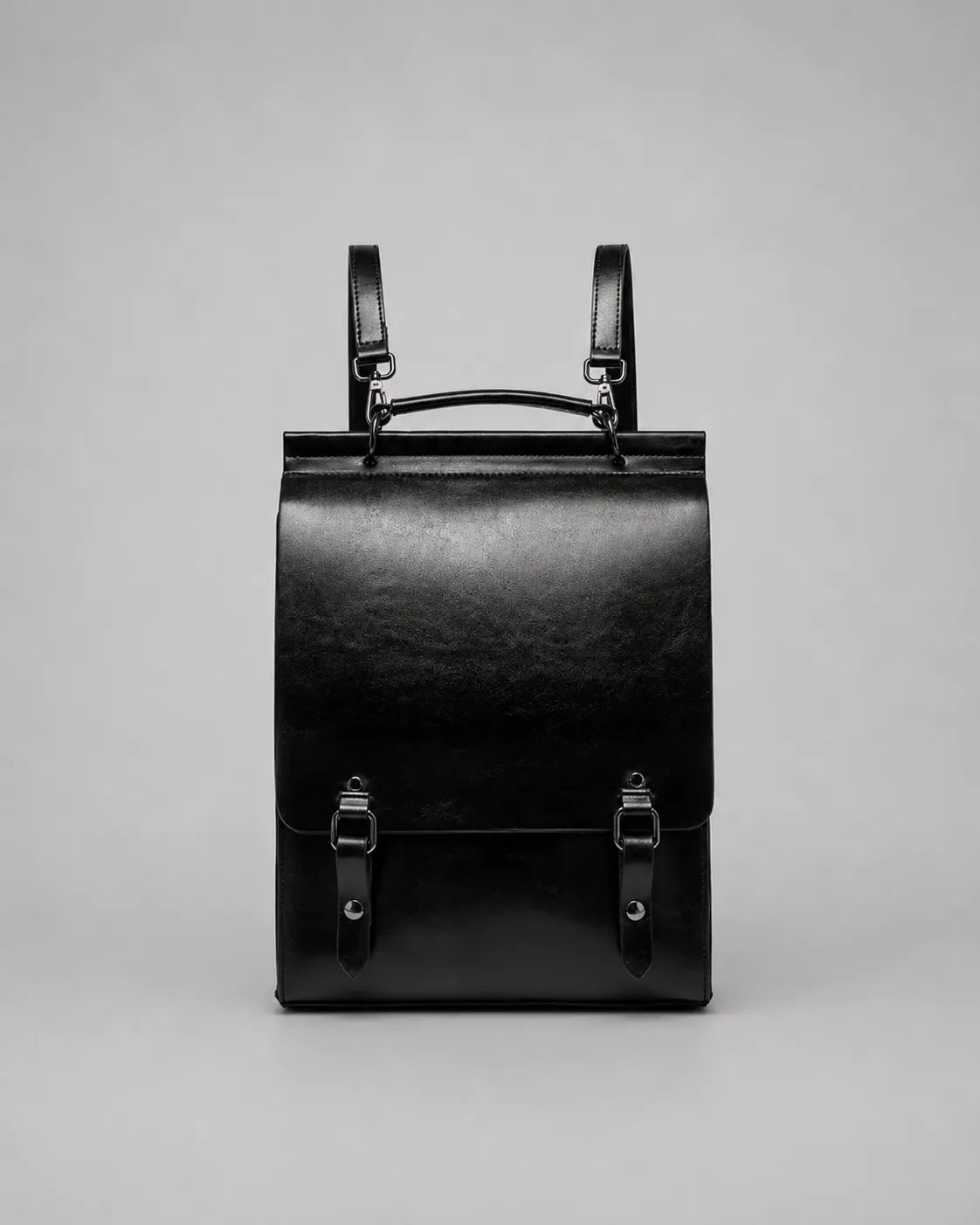 Front view of the Heritage Leather Backpack in Black genuine leather, designed with a structured profile, flap closure, top handle, adjustable shoulder straps and premium metal hardware.