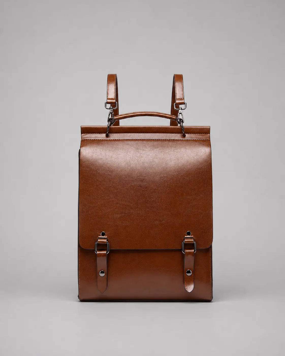 Front view of the Heritage Leather Backpack in Brown genuine leather, featuring a structured silhouette, flap closure, top handle, adjustable shoulder straps and premium hardware.