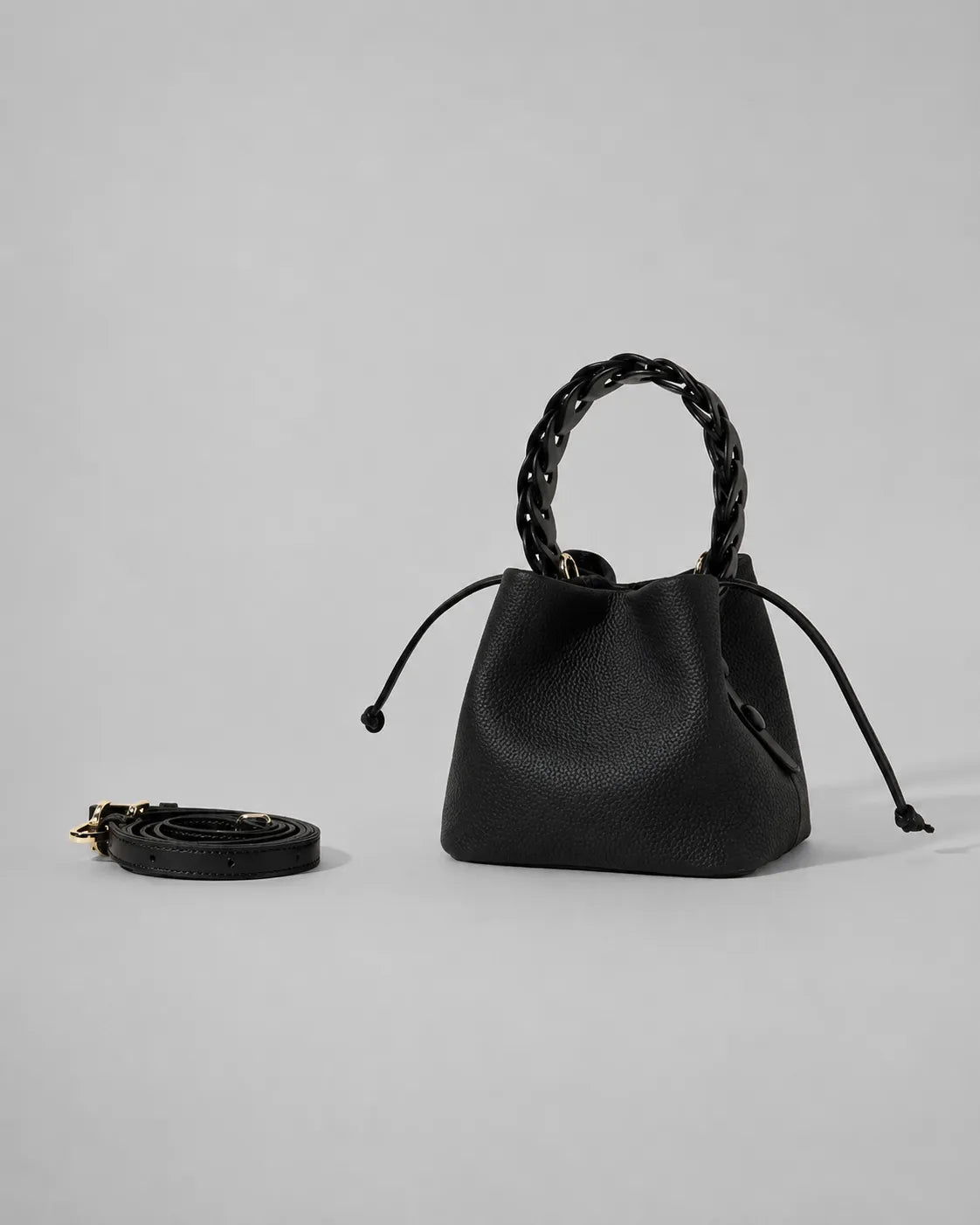 Front view of the Léonie genuine leather bucket bag in Black featuring a braided leather top handle, drawstring closure and modern statement bucket silhouette by Malena London.