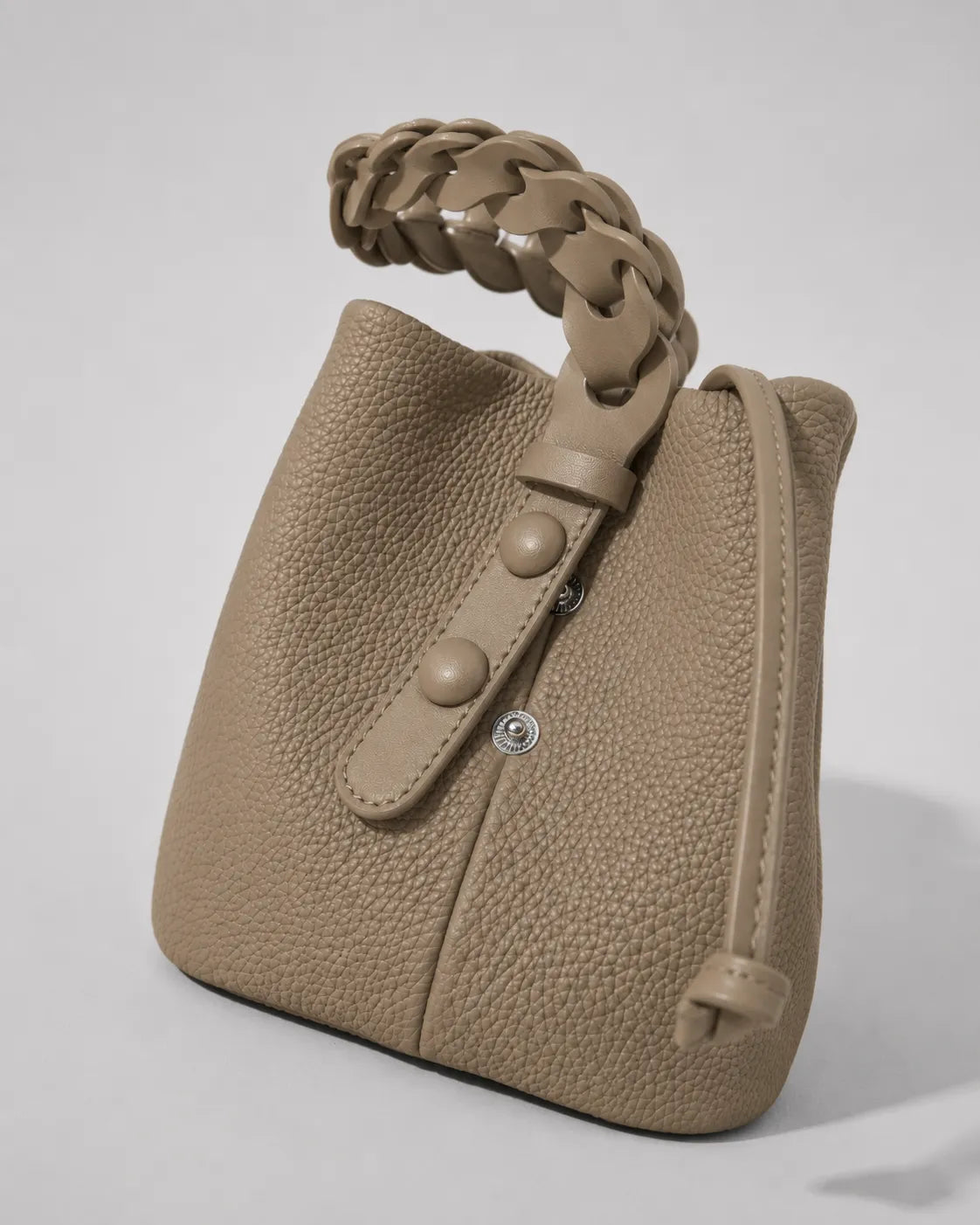 Close-up detail of the Léonie genuine leather bucket bag in Elephant Gray showcasing the sculptural braided leather handle, premium textured leather and refined craftsmanship by Malena London.