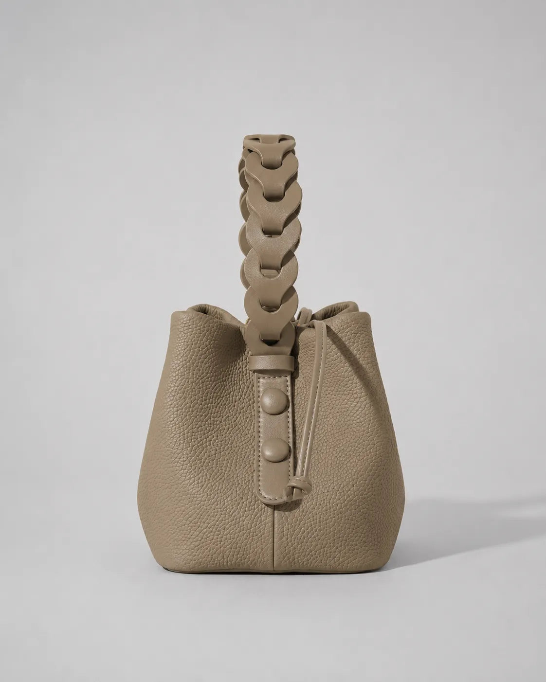 Side view of the Léonie genuine leather bucket bag in Cookie featuring the sculptural braided leather handle, drawstring closure, soft bucket silhouette and premium textured leather construction by Malena London.