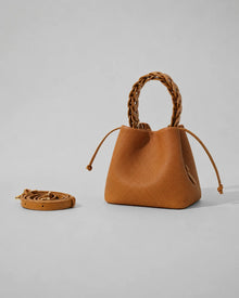 Léonie genuine leather bucket bag in Brown featuring a sculptural braided top handle, removable adjustable shoulder strap, drawstring closure and softly structured silhouette by Malena London.