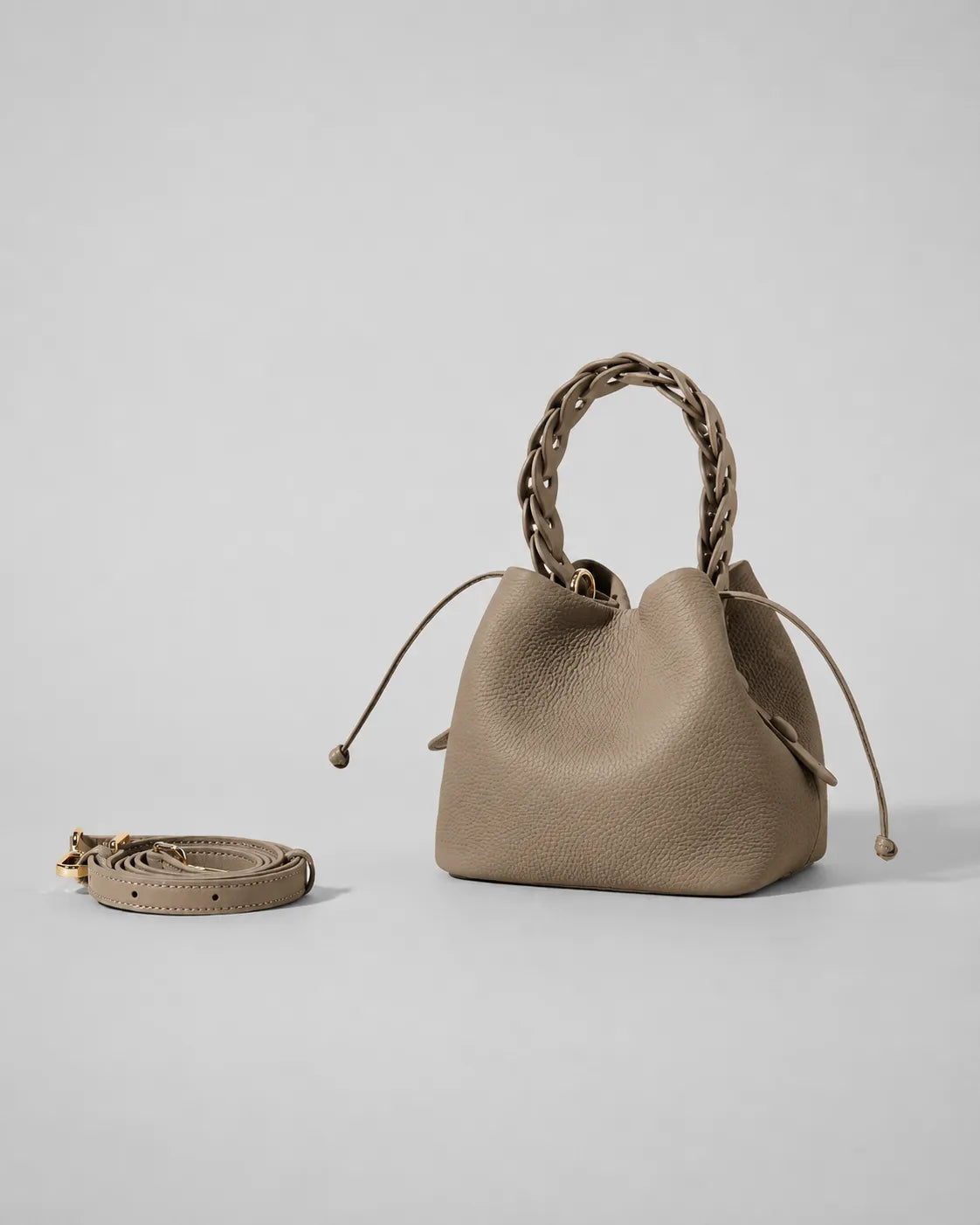 Léonie genuine leather bucket bag in Cookie displayed with removable adjustable shoulder strap and braided leather top handle, showcasing versatile handheld, shoulder and crossbody carrying options by Malena London.