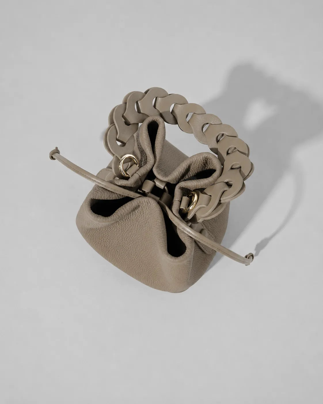 Top view of the Léonie genuine leather bucket bag in Elephant Gray displaying the drawstring closure, spacious interior opening and signature braided leather handle by Malena London.