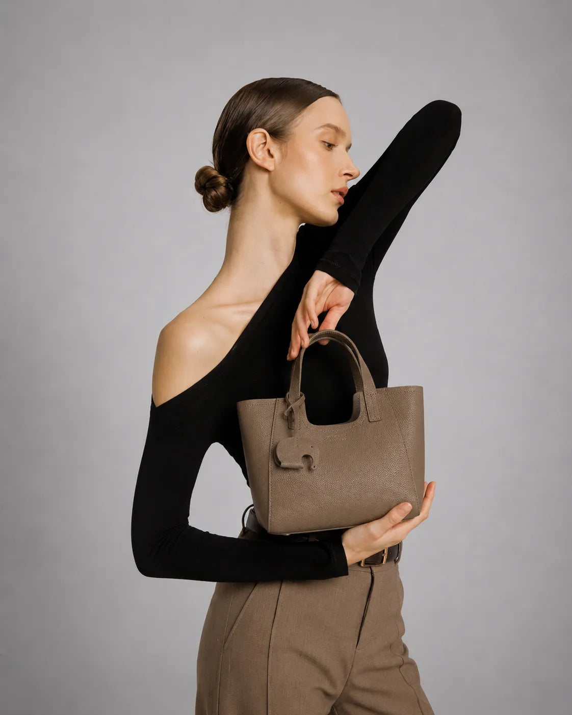 Woman holding The Louise Elephant Gray women's leather handbag. Minimalist genuine leather bag designed for everyday elegance with a timeless quiet luxury aesthetic.
