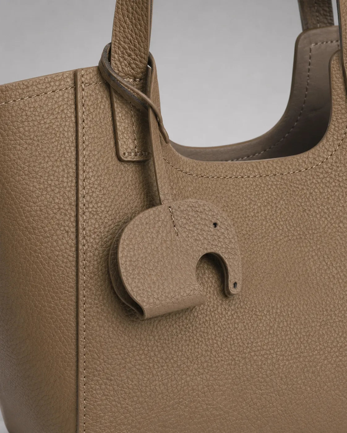 Close-up detail of the Louise genuine leather tote bag showcasing the signature elephant leather charm and premium pebbled leather texture.