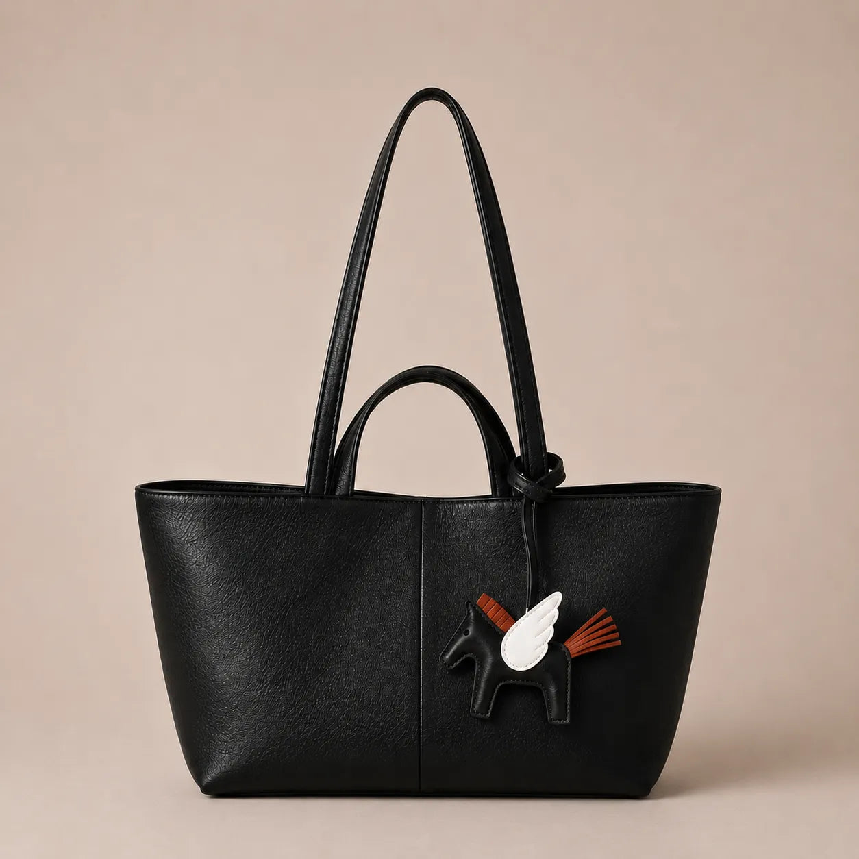 Leather bag charm accessory attached to a premium black tote bag for elegant handbag personalisation by Malena London