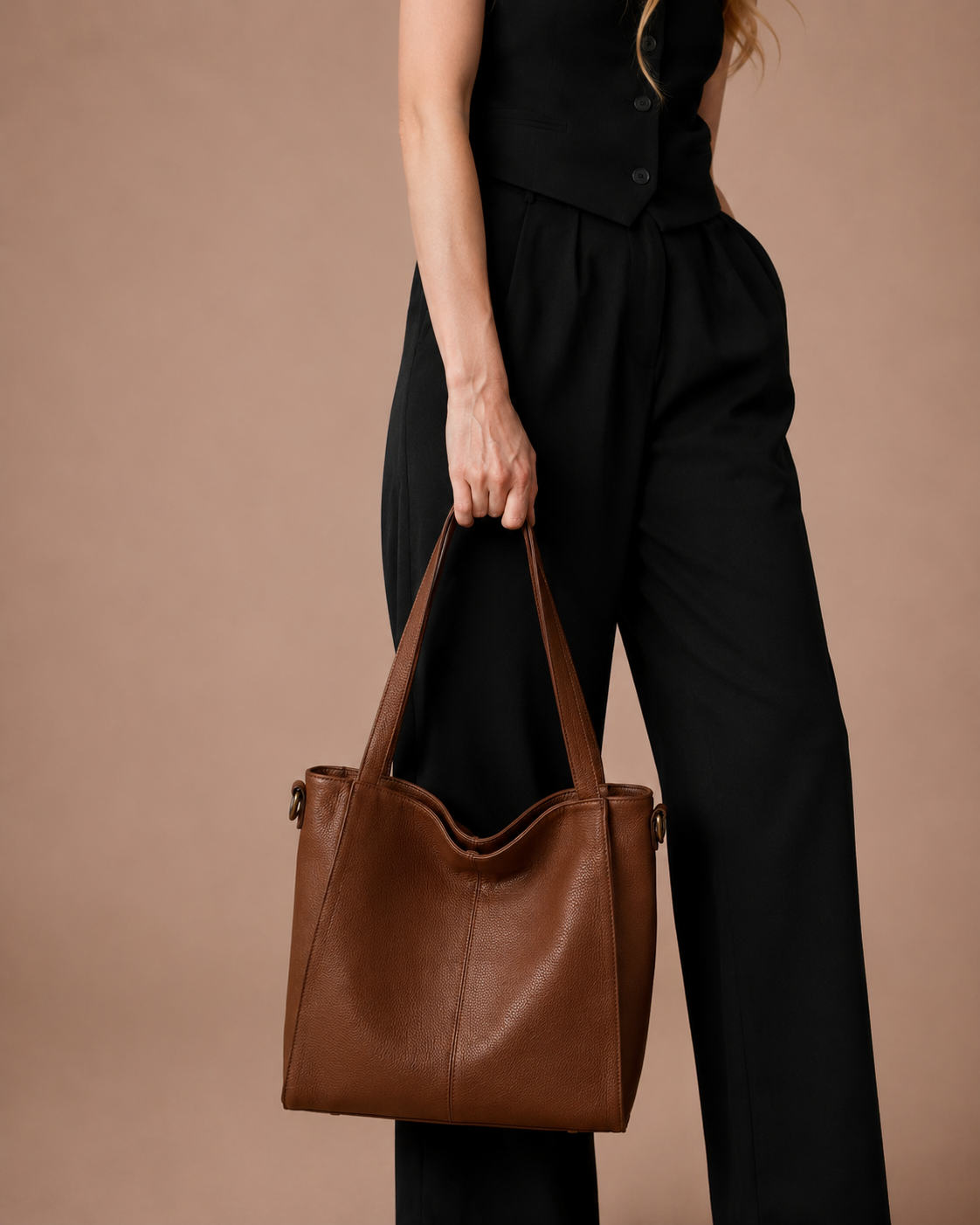 Woman carrying the Eleanor genuine leather work tote bag in Brown. Spacious women's leather handbag with structured silhouette, premium first-layer cowhide leather and elegant design for work, commuting and everyday use.