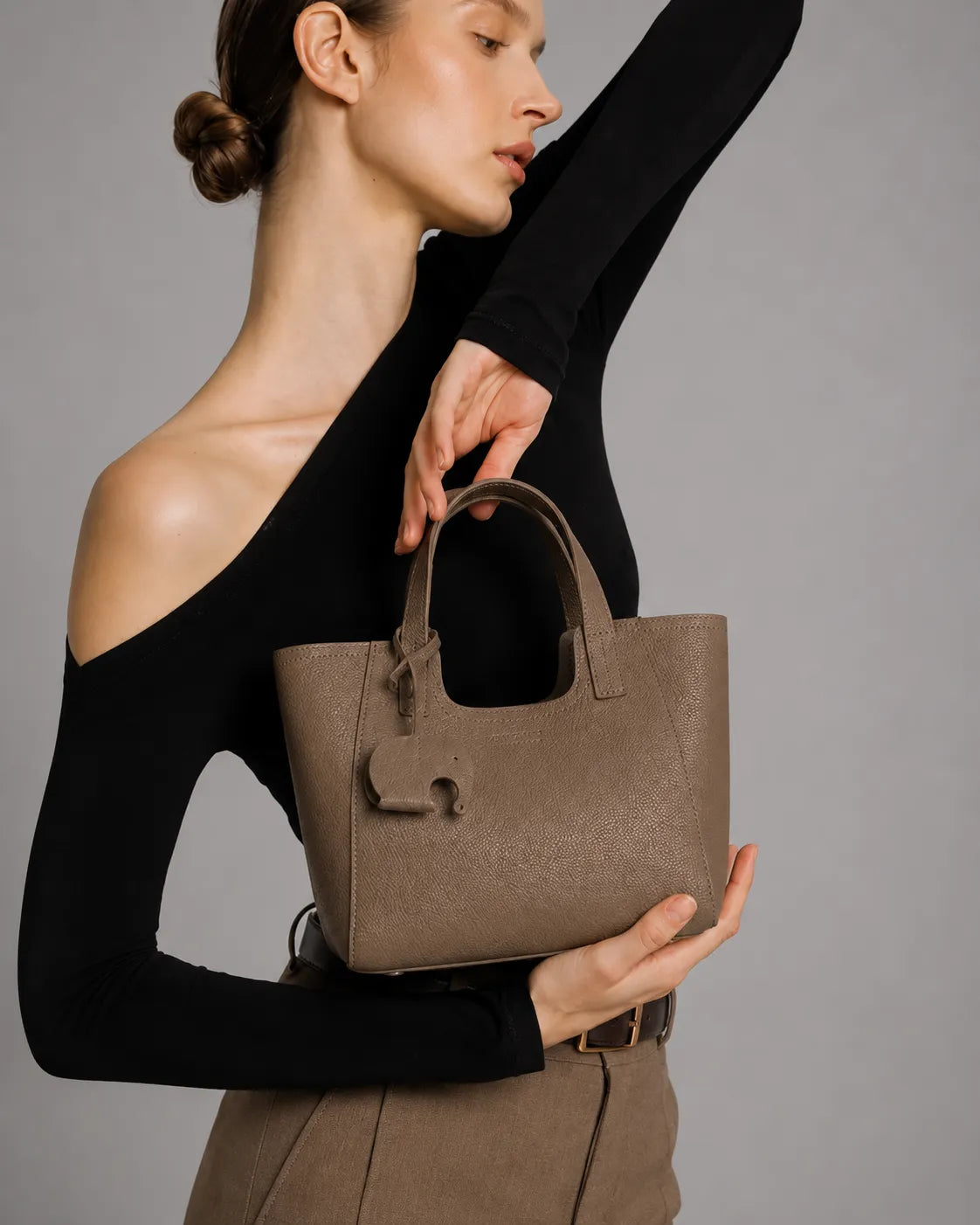 Editorial lifestyle image of the Louise women's genuine leather handbag in Elephant Gray. Compact leather tote with structured silhouette, premium pebbled leather and refined minimalist style for modern women.