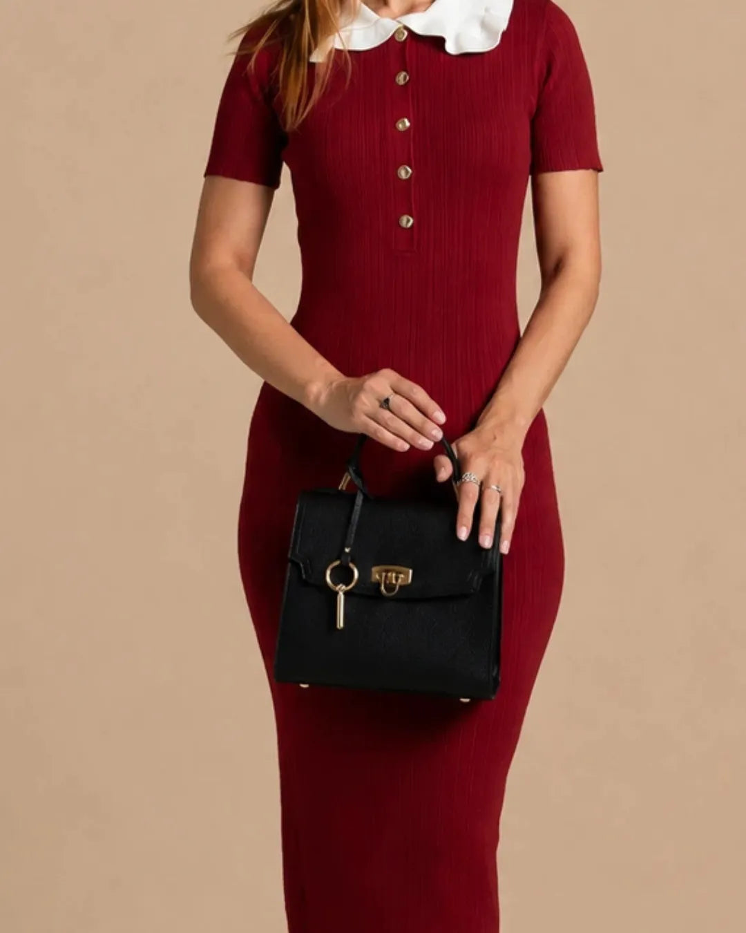 Model holding The Beatrice genuine leather top handle bag by hand, showcasing its structured silhouette, signature turn-lock closure, premium cowhide leather and elegant gold-tone hardware.