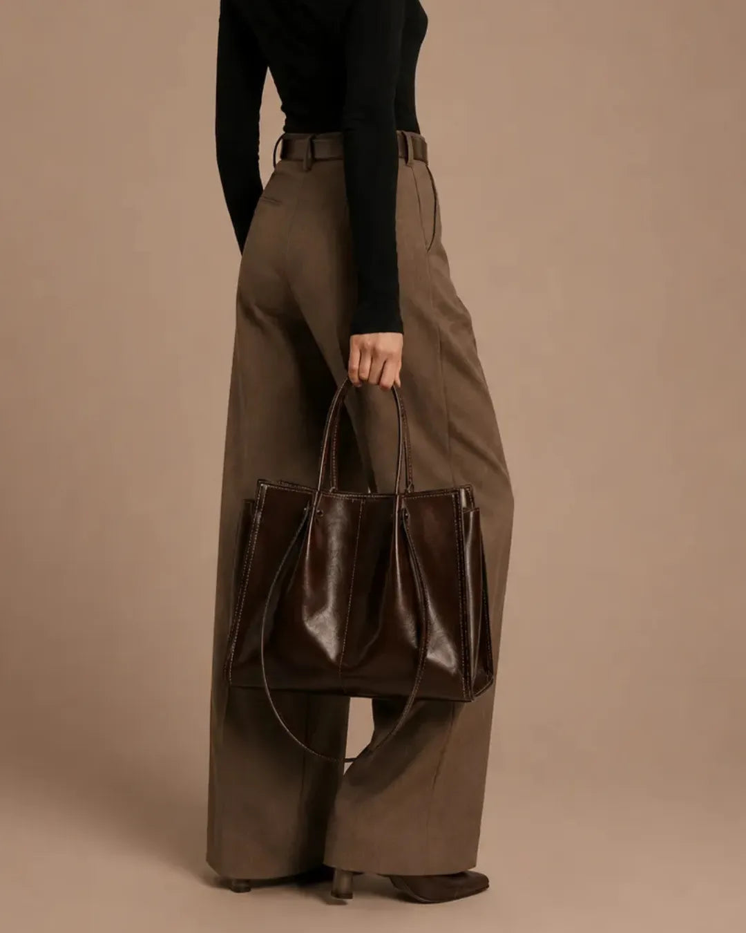 Rear view of a model carrying The Edith dark chocolate genuine leather tote bag, highlighting its structured shape, premium leather finish and timeless design for modern everyday wear.