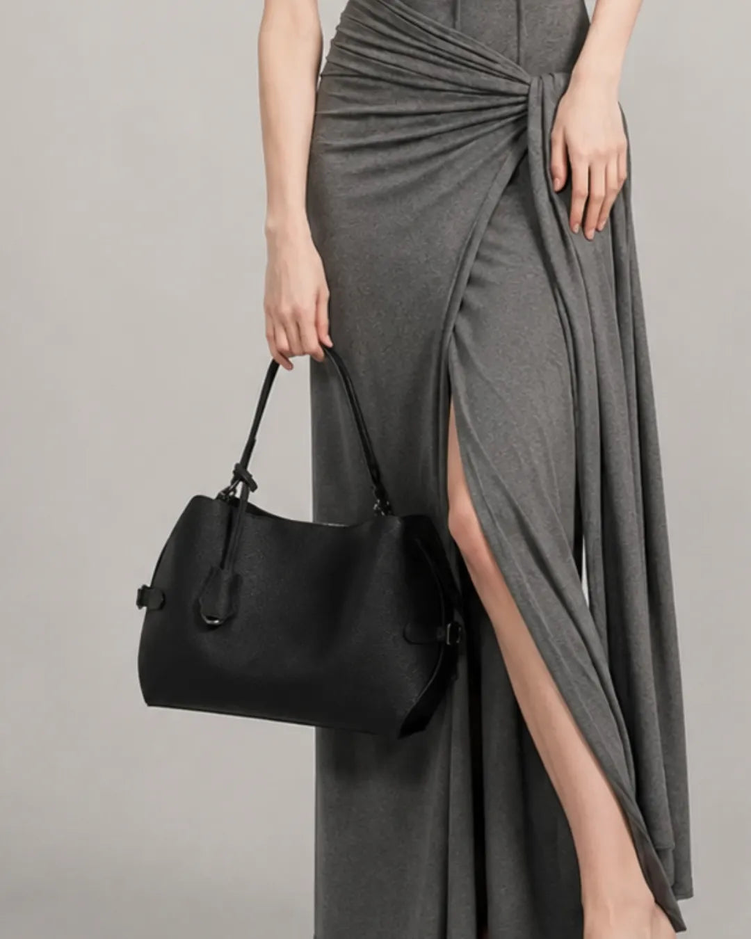Model carrying the black The Eliza genuine leather shoulder bag by hand, highlighting its elegant proportions, lightweight design and refined silhouette for everyday wear.