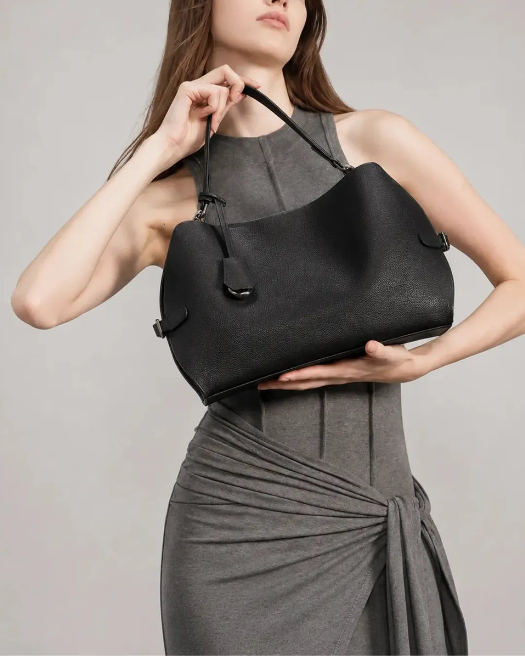 Front view of the black The Eliza genuine leather shoulder bag held by the model, featuring a softly structured silhouette, premium cowhide leather and timeless minimalist styling.