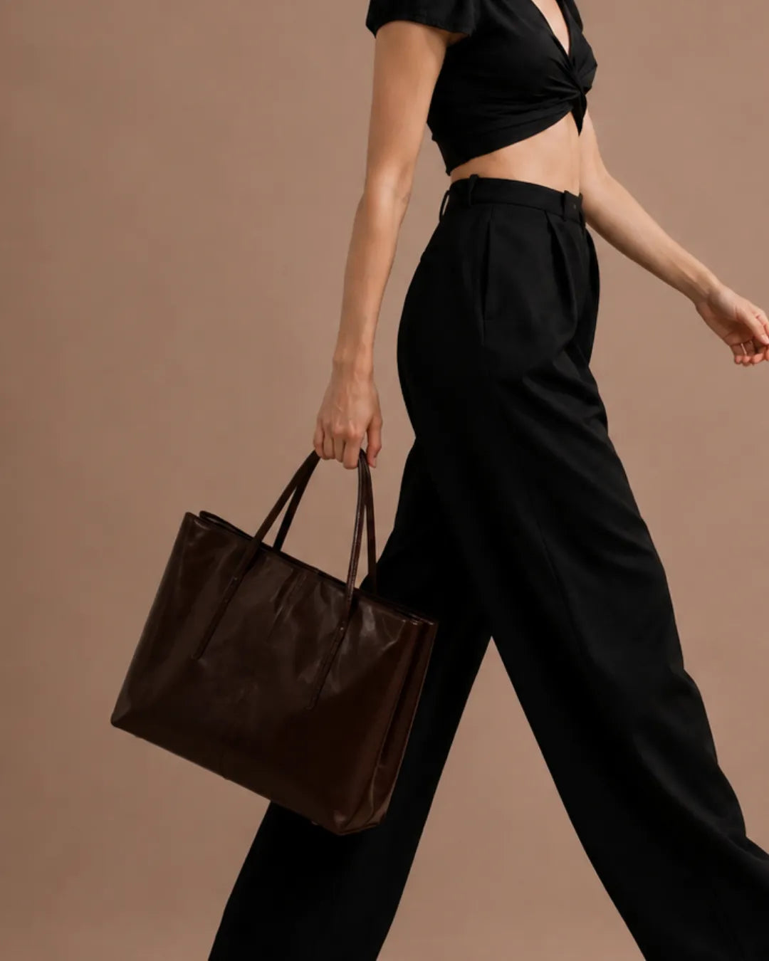 Model holding The Margaux dark chocolate genuine leather tote bag, featuring a spacious structured silhouette, premium genuine leather and timeless everyday style for work, travel and commuting.