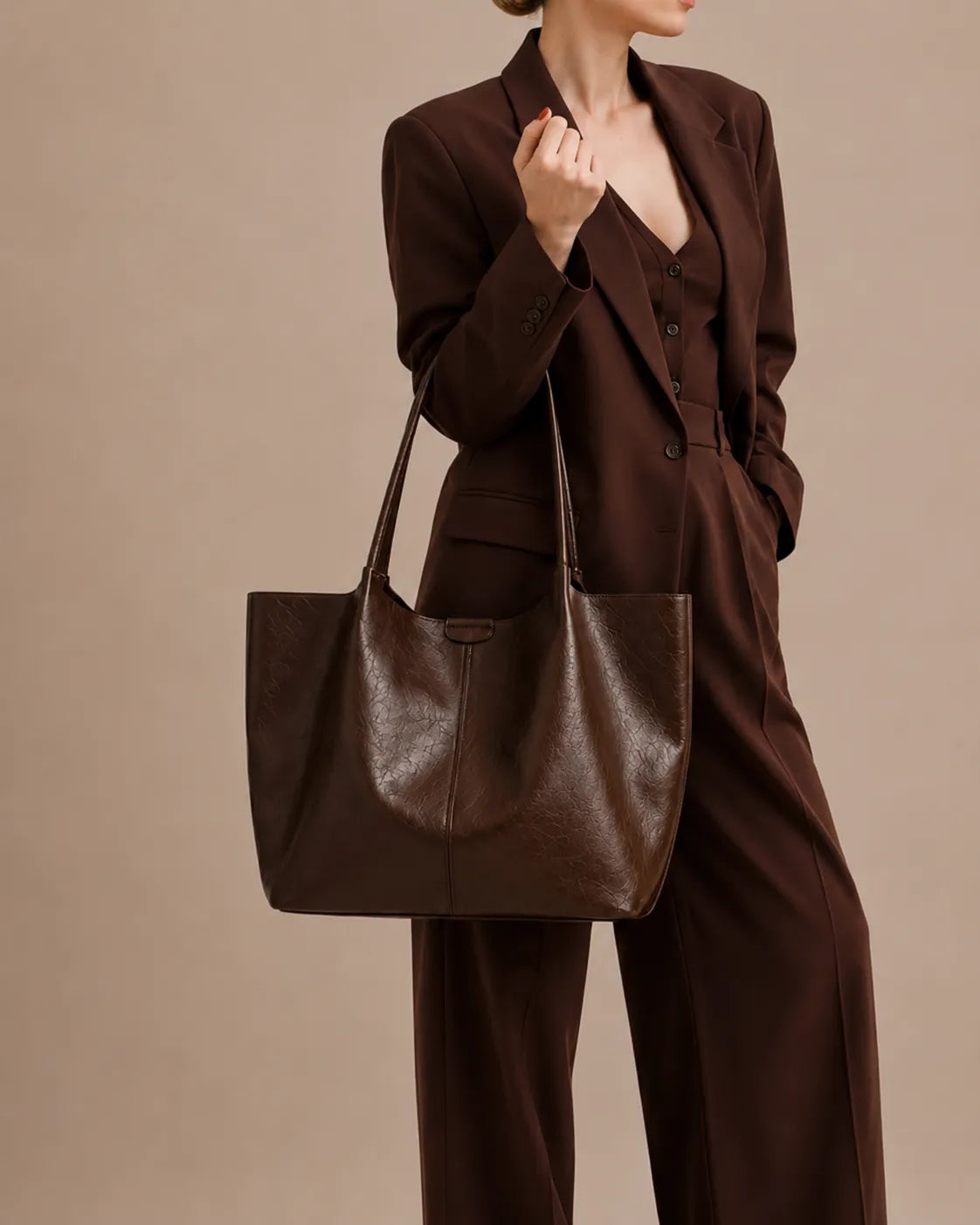 Lifestyle image of a model carrying The Valentina dark chocolate genuine leather tote bag, featuring a spacious interior, soft structured silhouette and refined everyday elegance for modern women.