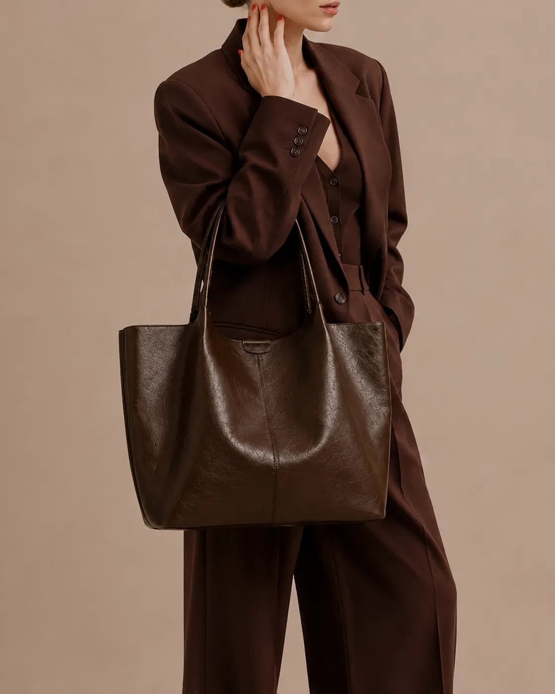 Model wearing The Valentina dark chocolate genuine leather tote bag over the shoulder, highlighting its soft leather construction, generous capacity and timeless everyday style for work and commuting.