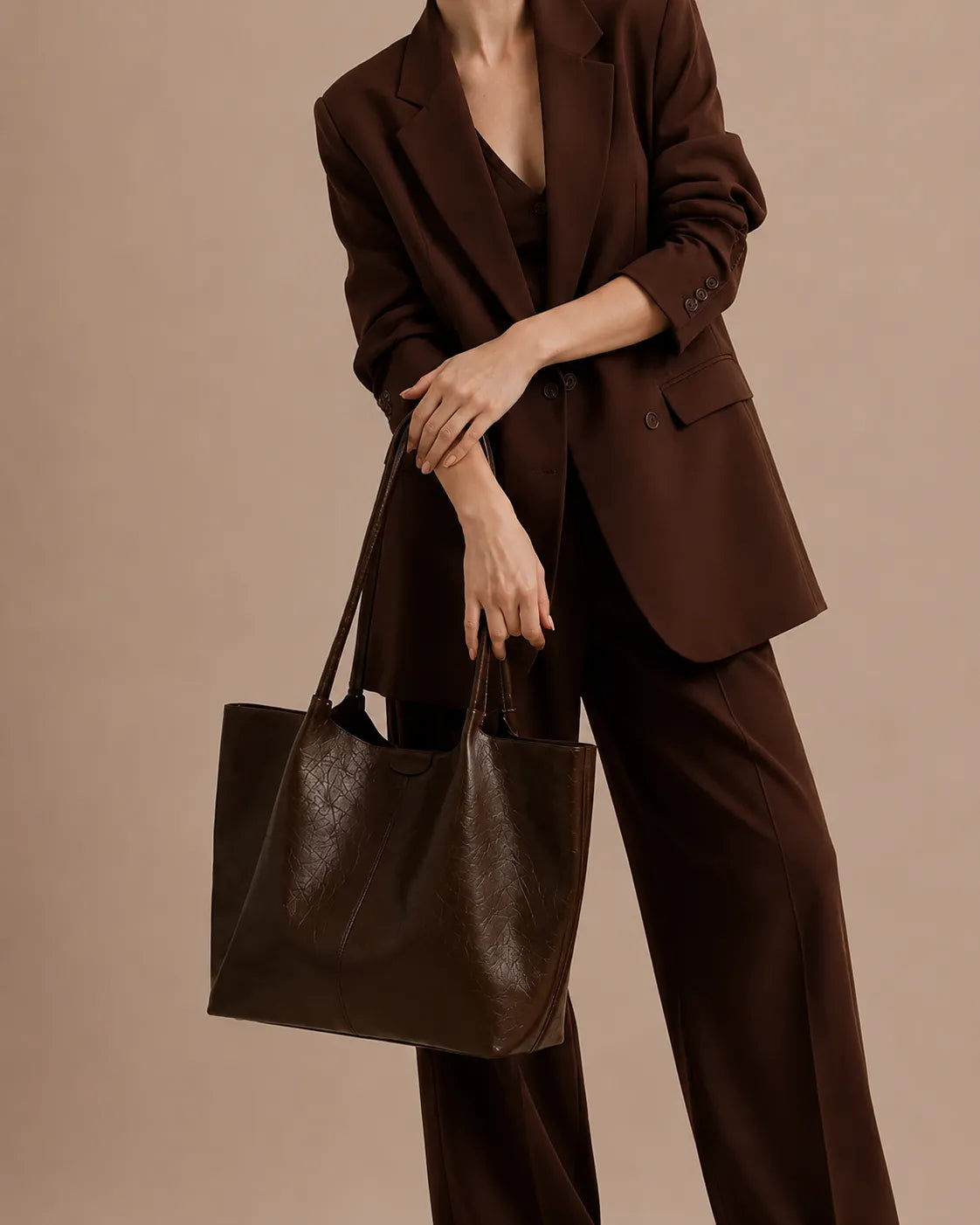 Model holding The Valentina dark chocolate genuine leather tote bag, showcasing its spacious soft-structured silhouette, premium genuine leather and elegant design for work, travel and everyday use.