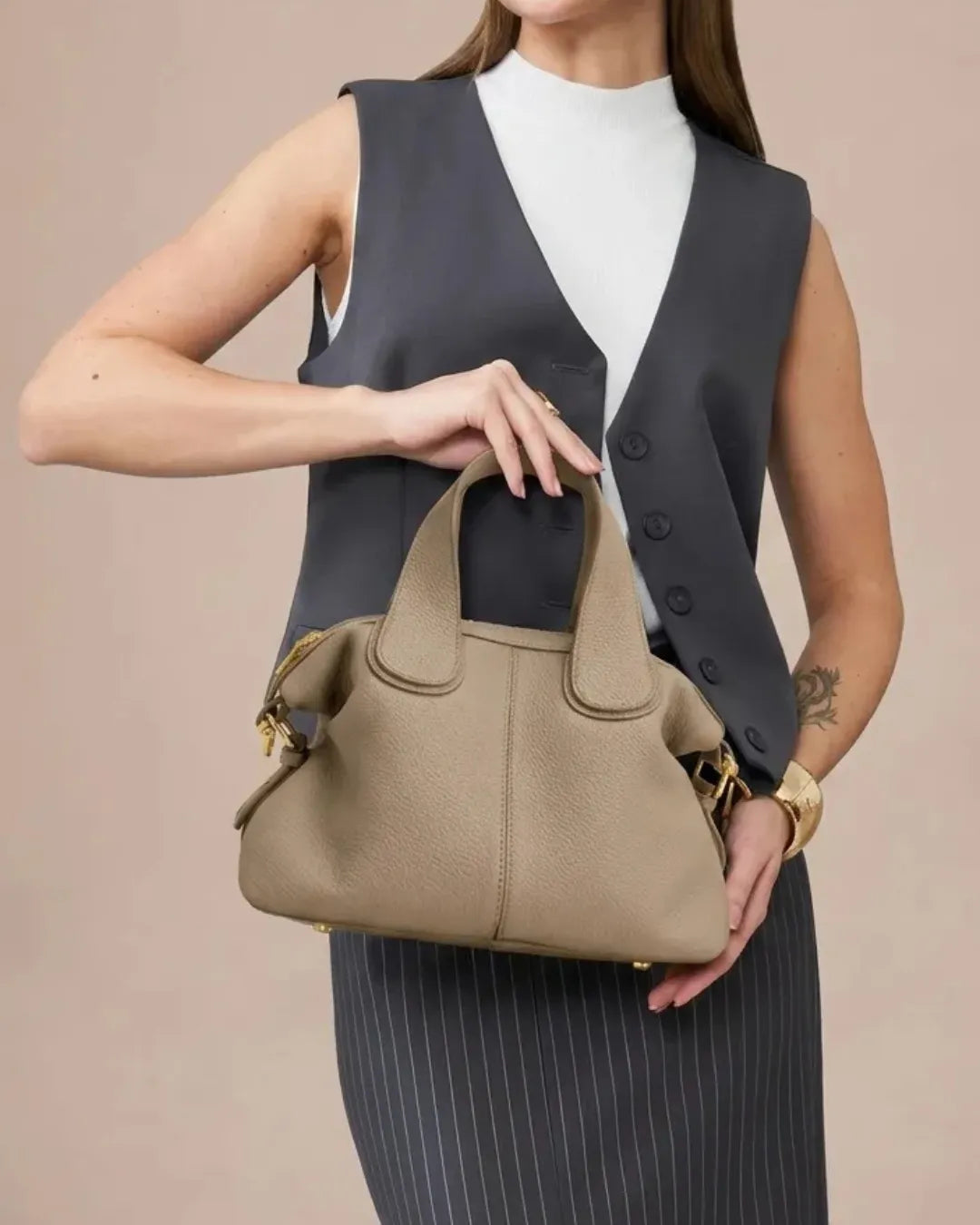 Close-up of The Victoire genuine leather dumpling bag in Elephant Gray highlighting the premium pebbled leather texture, structured top handles and elegant gold-tone hardware for a timeless luxury finish.