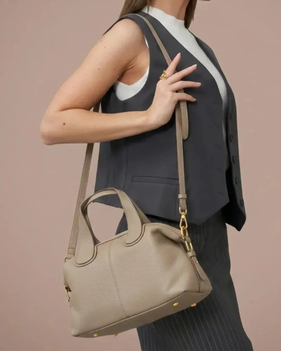 Woman wearing The Victoire genuine leather dumpling bag in Elephant Gray over the shoulder. Elegant women's leather handbag crafted from premium top-layer cowhide leather for work, commuting, travel and everyday wear.