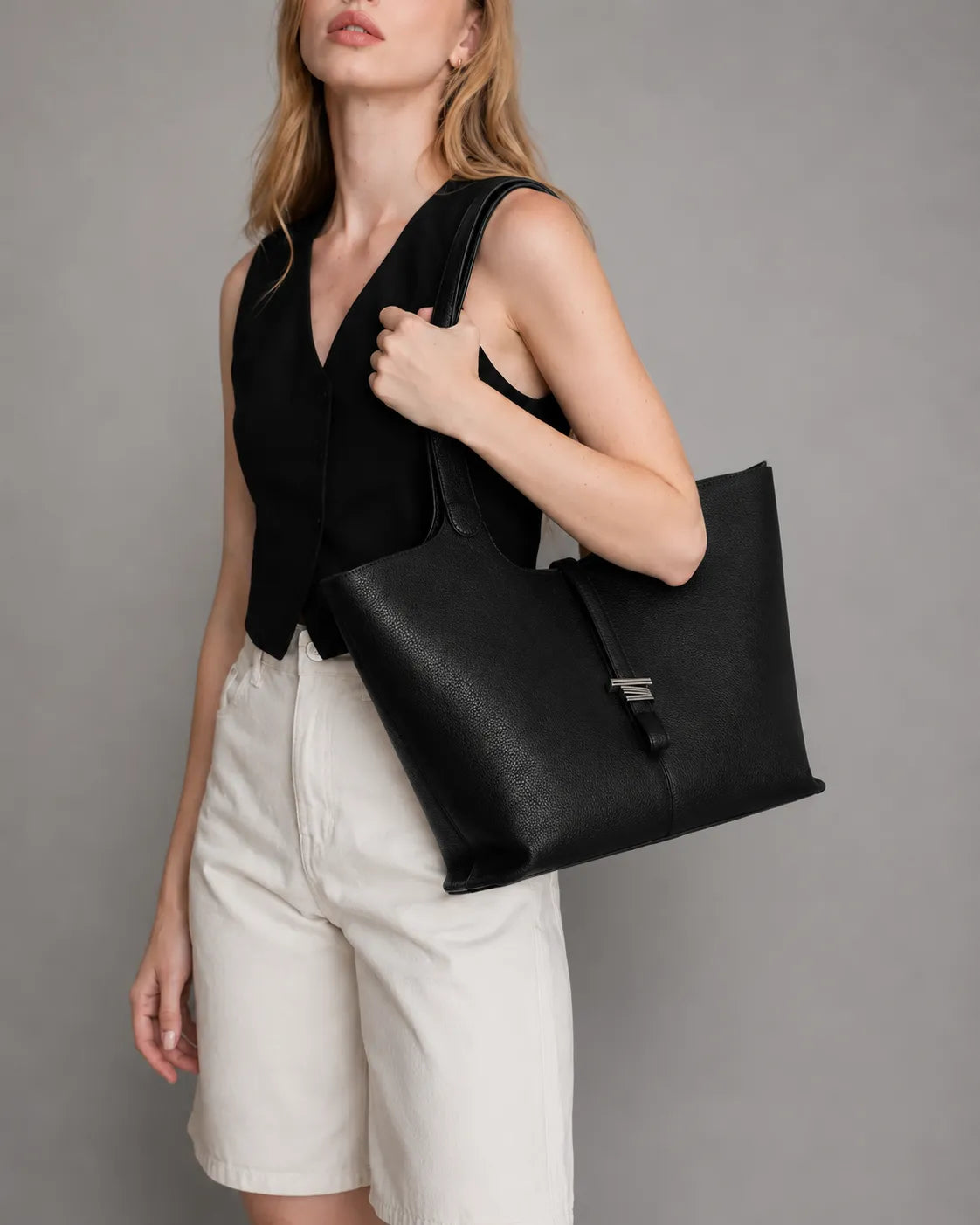 Lifestyle image of the Victoria women's genuine leather work tote bag in Black. Spacious shoulder handbag with a timeless minimalist design, crafted for office days, travel and everyday city living.