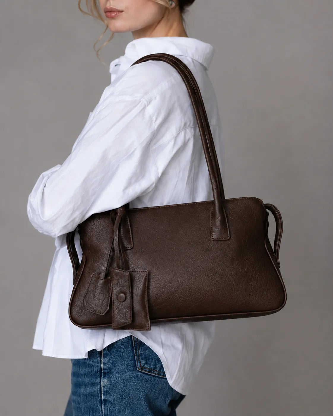 Side view of model carrying The Georgia genuine leather shoulder bag in Dark Chocolate, premium women's leather handbag with a soft structured design.