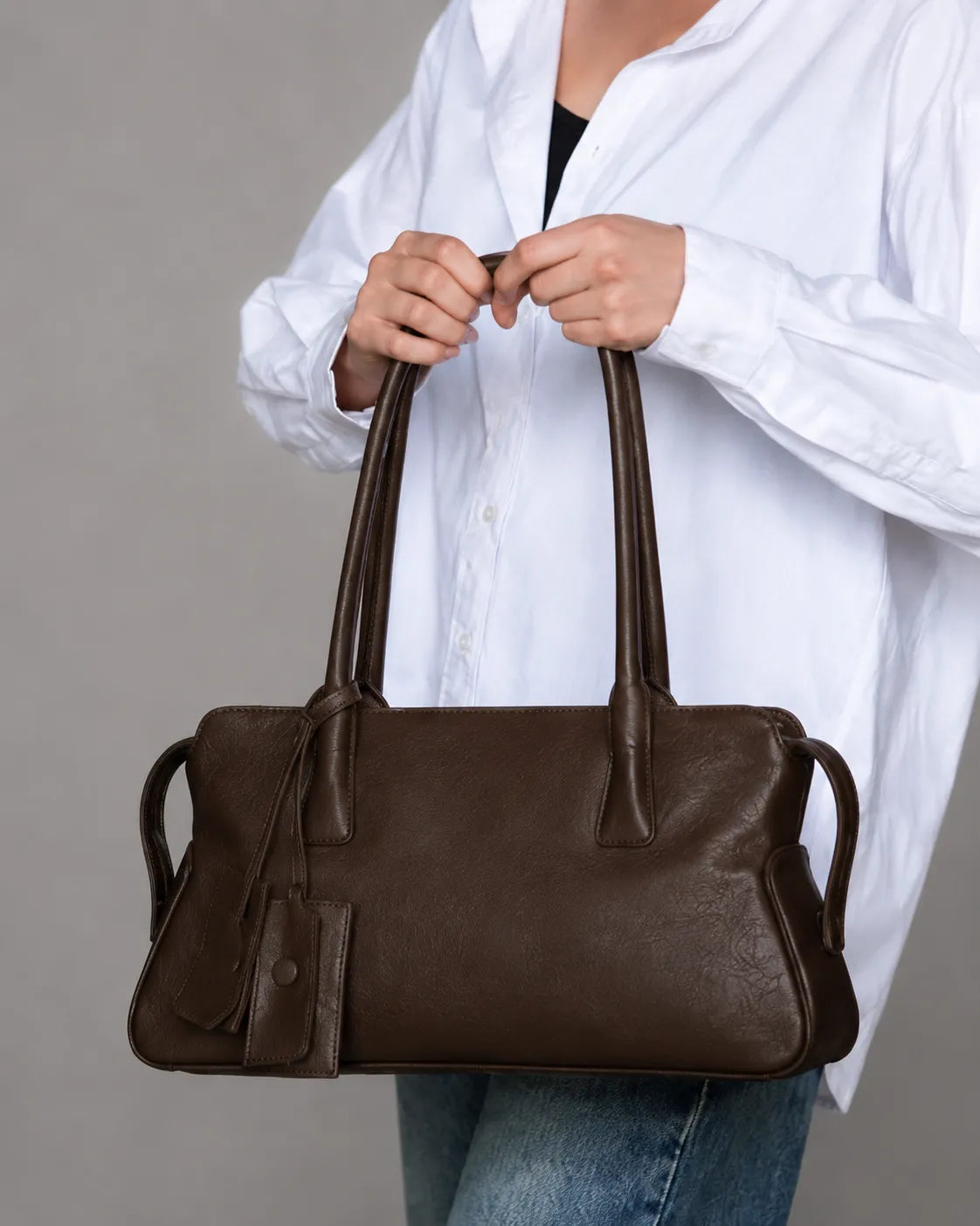 Model holding The Georgia genuine leather shoulder bag in Dark Chocolate, luxury women's leather handbag with a soft structured silhouette for everyday elegance.