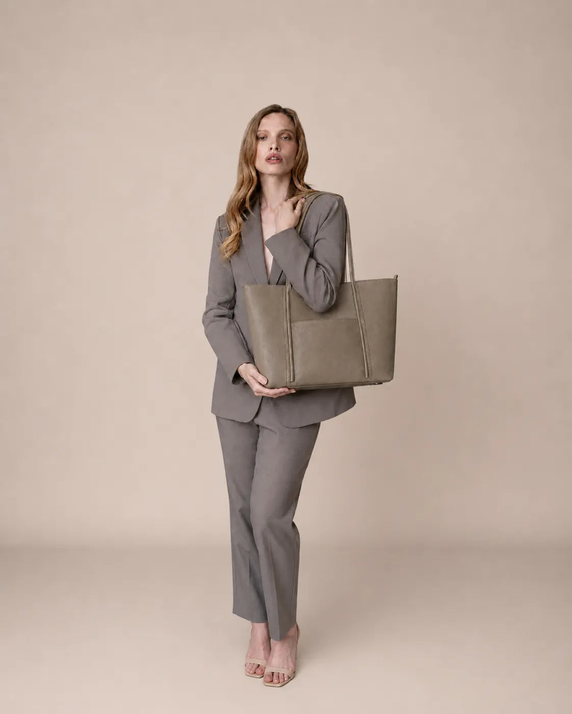 Model holding The Vivienne genuine leather tote bag in Elephant Gray, luxury women's leather handbag with a structured silhouette for work and everyday elegance.