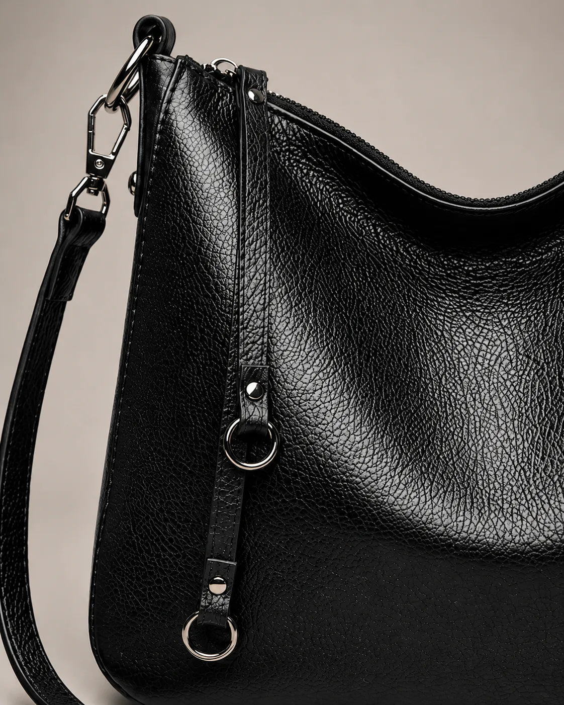 Close-up detail of the Noémie soft genuine leather hobo shoulder bag in black showing the leather texture and hardware.