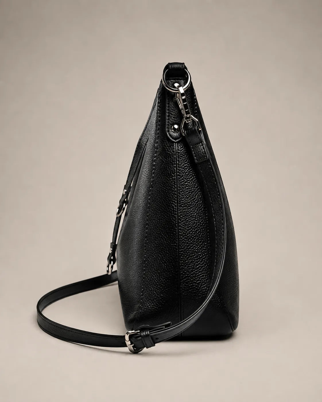 Side view of the Noémie soft genuine leather hobo shoulder bag in black showing the zip closure and straps.