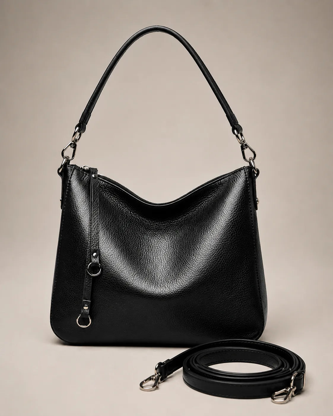 Front view of the Noémie soft genuine leather hobo shoulder bag in black with the detachable crossbody strap laid out.