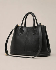 Angled view of the Odile large structured genuine leather tote bag in black showing the panelled silhouette and gold-tone hardware.