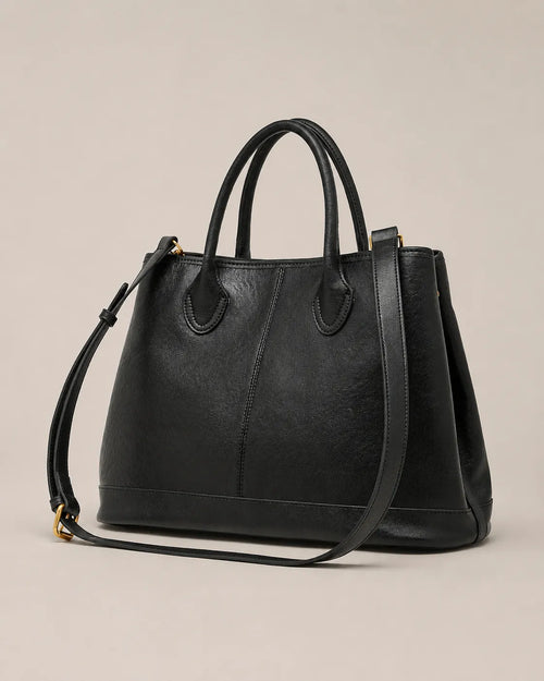 Angled view of the Odile large structured genuine leather tote bag in black showing the panelled silhouette and gold-tone hardware.