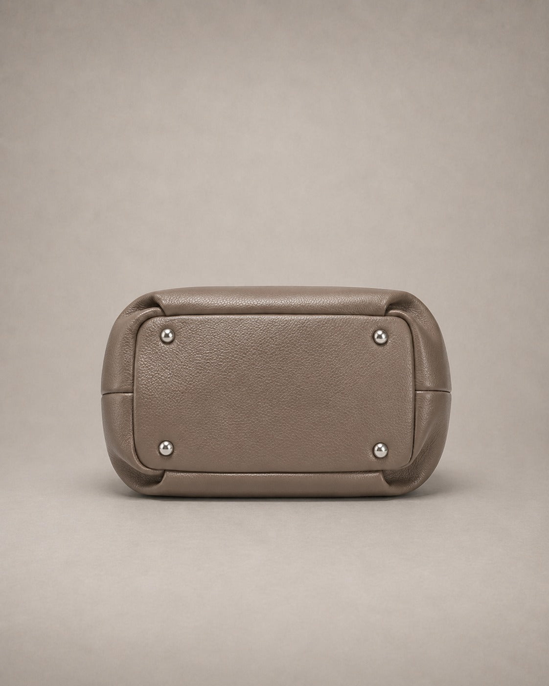 Bottom view of the Pauline genuine leather top handle crossbody bag in taupe highlighting the structured base with protective metal feet and premium leather craftsmanship by Malena London.