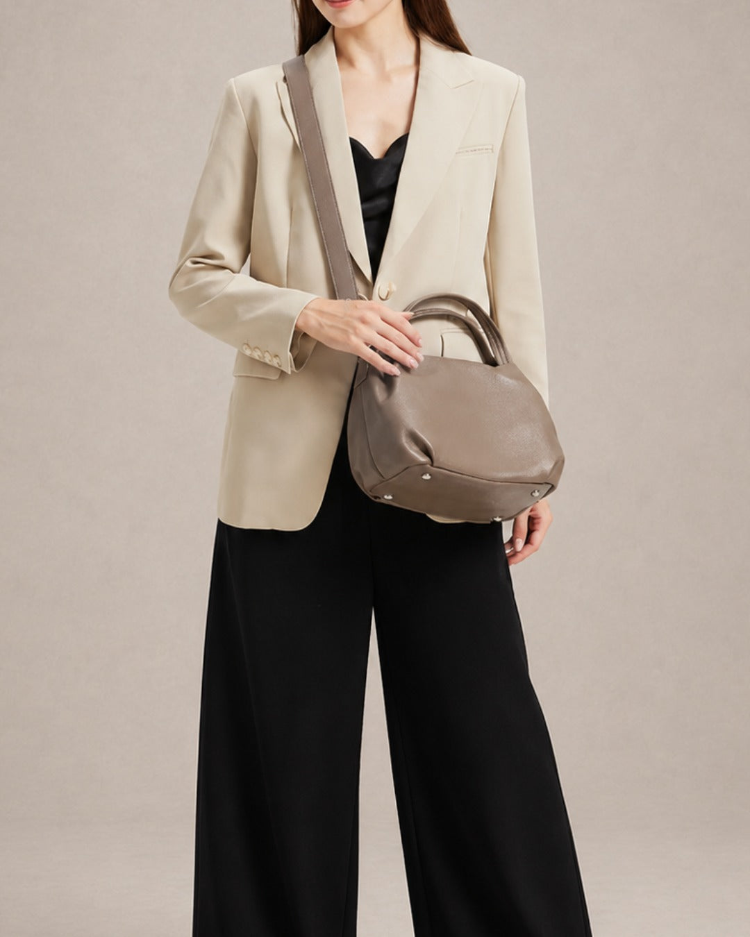 Woman wearing the Pauline genuine leather top handle crossbody bag in Taupe with the adjustable shoulder strap, showcasing elegant day-to-evening styling and premium pebbled leather by Malena London.