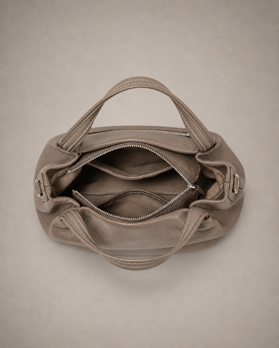 Interior of the Pauline genuine leather top handle crossbody bag in Taupe showing multiple organised compartments, zipped pocket and premium lining by Malena London.
