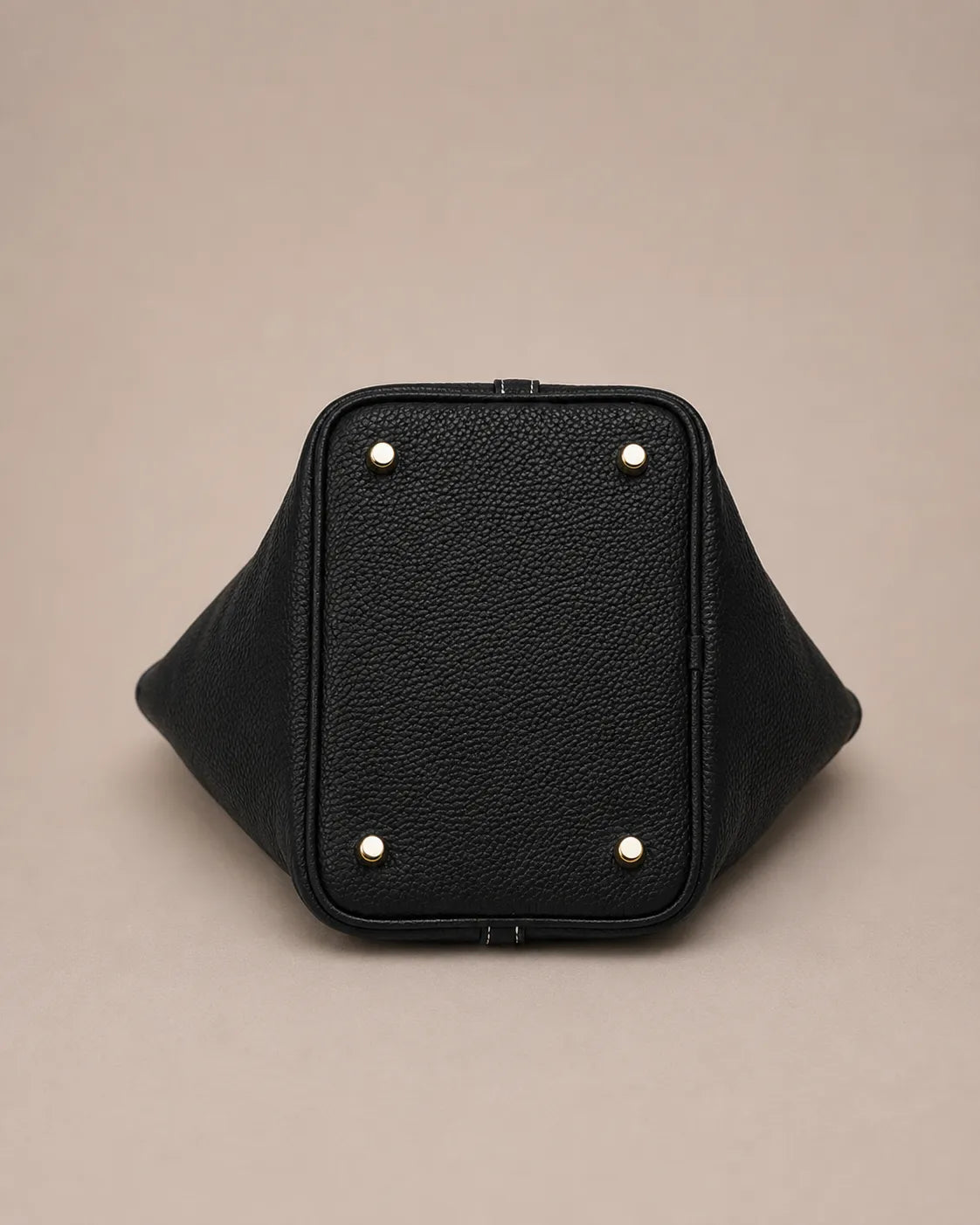 Bottom view of Scarlett genuine leather bucket tote bag featuring structured base and protective metal feet in black leather